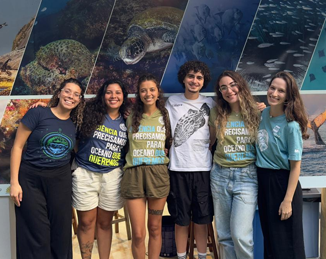 Seis integrantes da equipe do Projeto Coral Vivo lado a lado vestindo camisetas com a frase "A ciência que precisamos para o oceano que queremos".